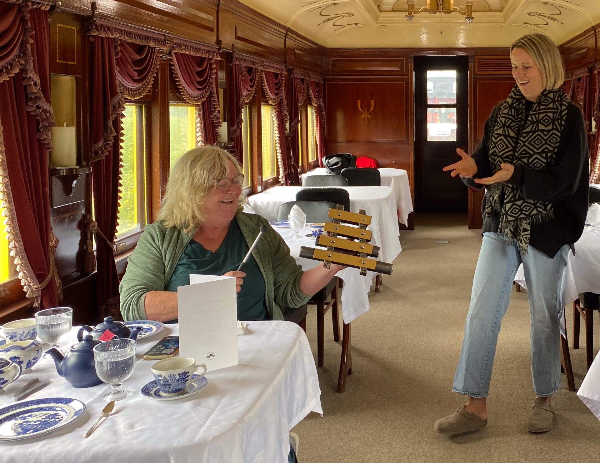 Guest Jane Finn (seated) learns about an antique dinner chime from Railway Museum of Eastern Ontario executive director Becky Allen.